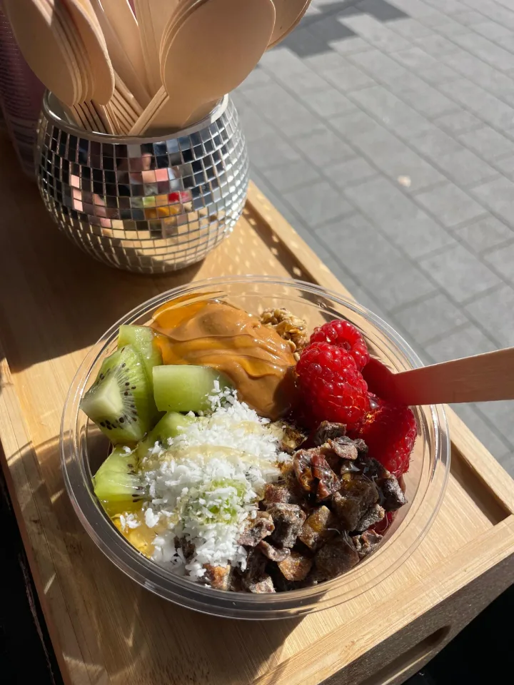 A bowl of fresh fruit, dates, coconut and peanut butter on the sunny counter