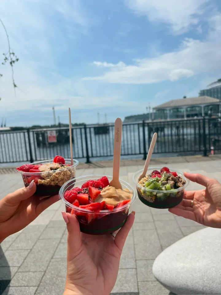 Three friends holding their freshly topped açaí bowls at Cardiff Bay